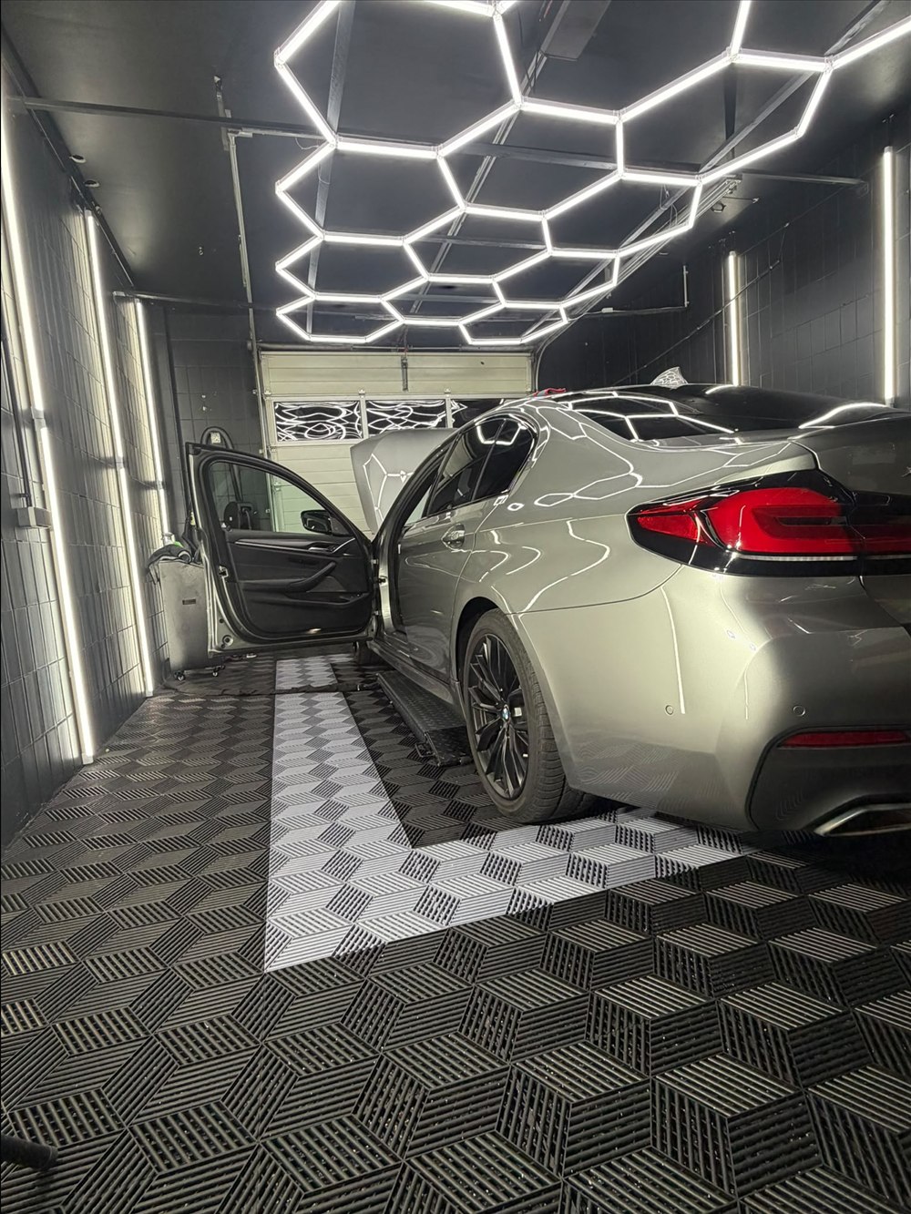 BMW 545e in Grau, Heckansicht mit geöffneter Tür im Detailing-Studio in Peine