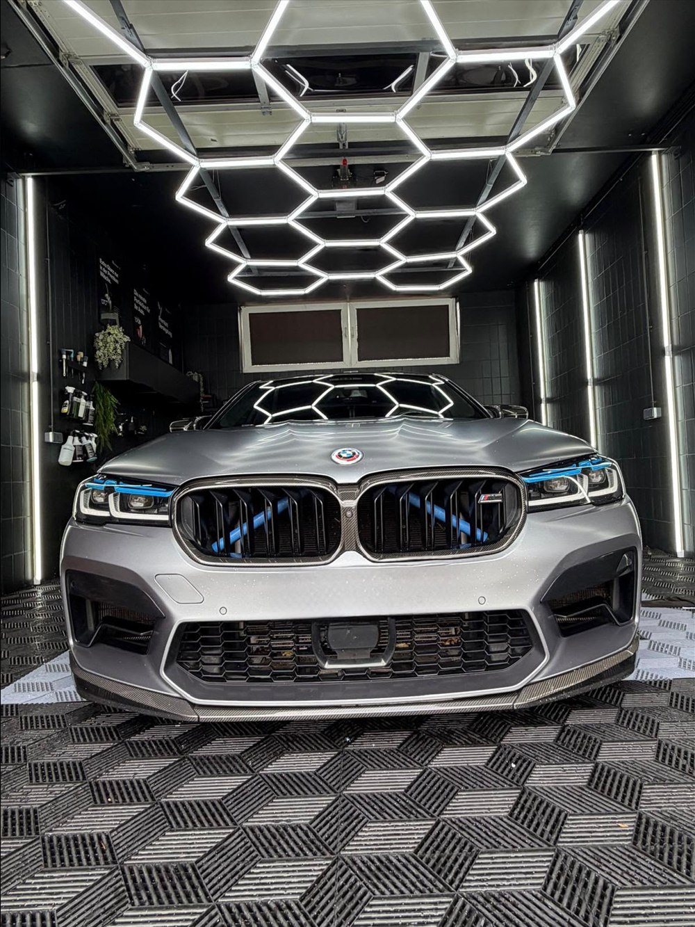 BMW M5 in Silber unter dem Hexagon-Licht mit glänzender Front