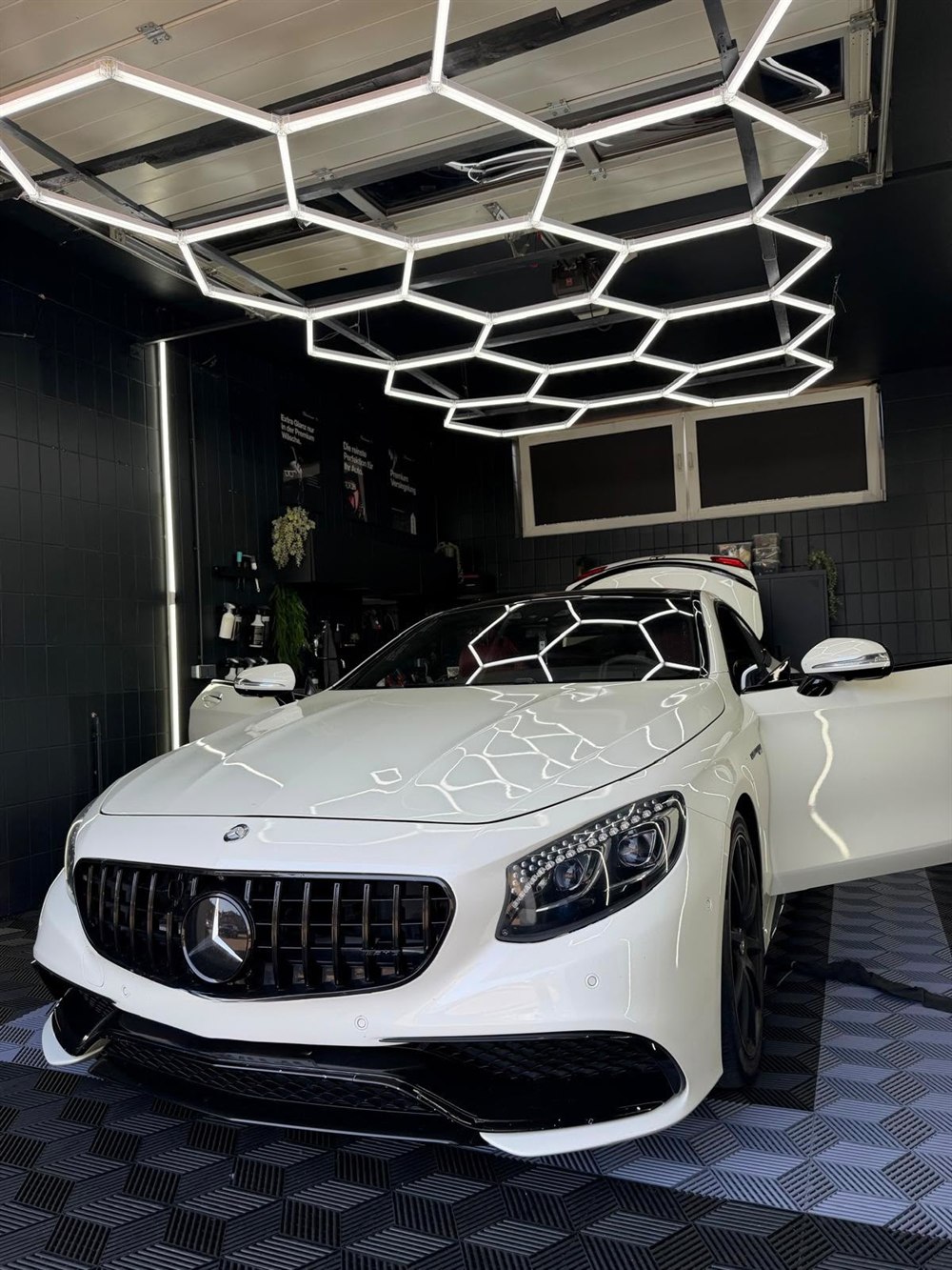 Mercedes-AMG S63 Coupé in Weiß, frontale Ansicht mit Lackreflexionen im Detailing-Studio