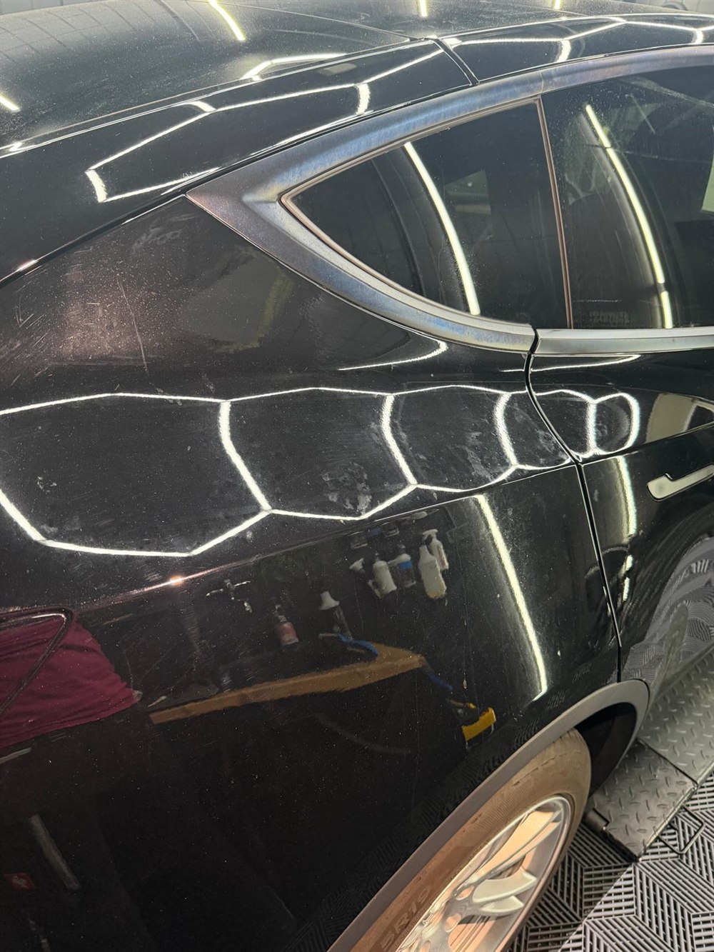 Tesla Model Y in Schwarz mit Hexagon-Reflexion auf dem Lack im Detailing-Studio